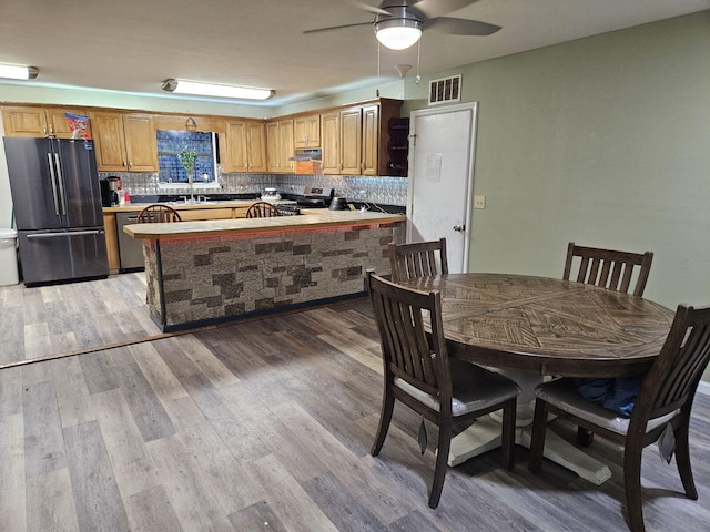 kitchen featuring ceiling fan, sink, tasteful backsplash, light hardwood / wood-style floors, and appliances with stainless steel finishes