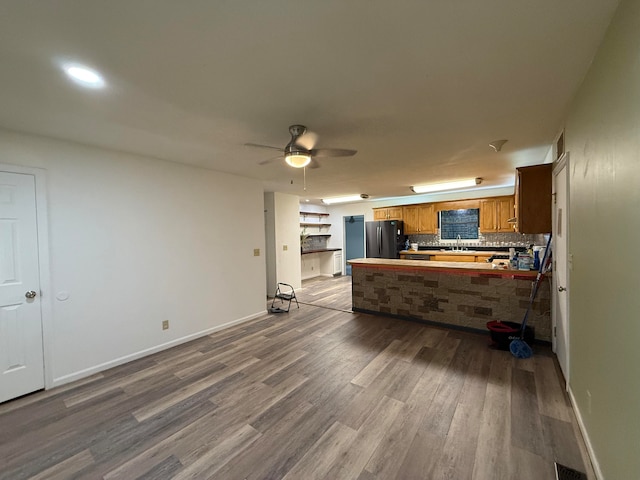 kitchen with kitchen peninsula, stainless steel fridge, ceiling fan, sink, and wood-type flooring