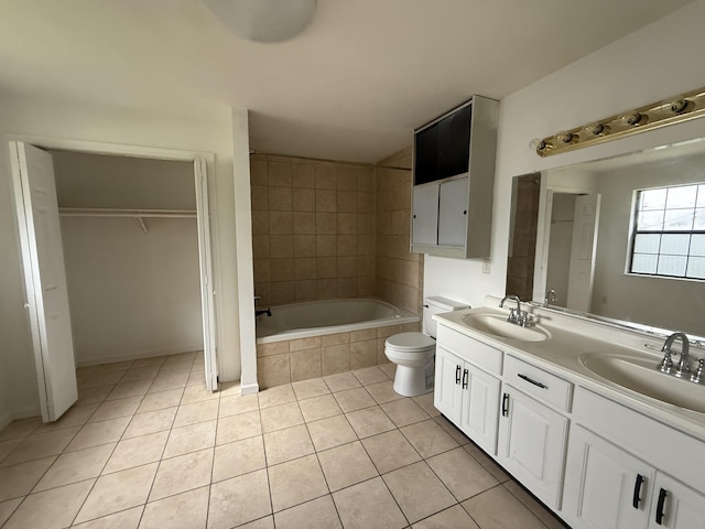 full bathroom featuring a relaxing tiled tub, tile patterned flooring, a sink, and toilet