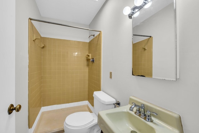 bathroom featuring sink, toilet, and tiled shower