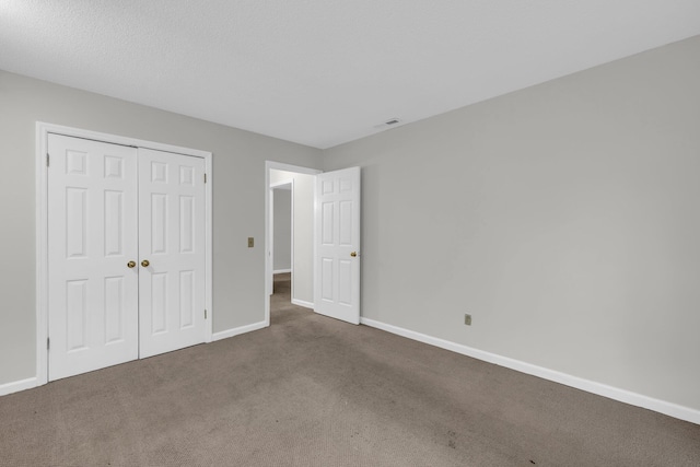 unfurnished bedroom featuring dark carpet and a closet