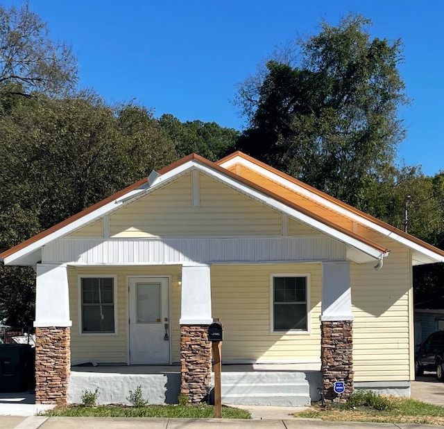 bungalow with covered porch and stone siding