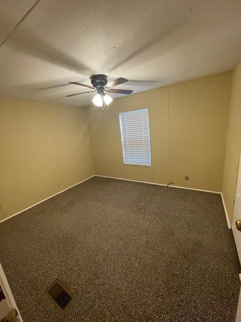 spare room featuring ceiling fan, a textured ceiling, and carpet