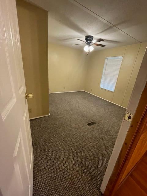 empty room featuring dark carpet and ceiling fan