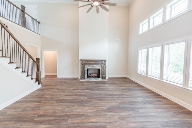 unfurnished living room featuring ornamental molding, dark hardwood / wood-style floors, and a towering ceiling