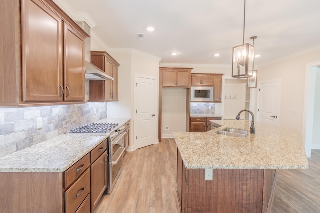 kitchen with stainless steel stove, decorative light fixtures, light wood-type flooring, and a kitchen island with sink