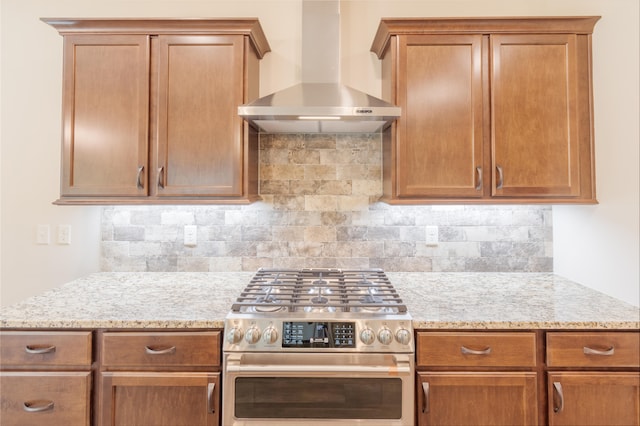 kitchen featuring light stone countertops, wall chimney range hood, backsplash, and double oven range