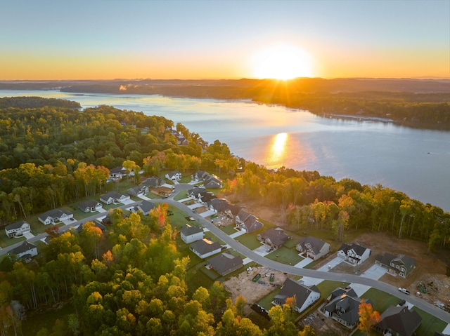 aerial view at dusk featuring a water view