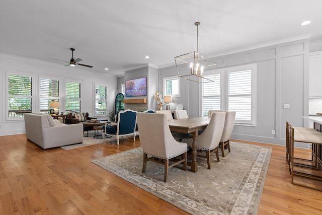 dining area with light hardwood / wood-style flooring, ceiling fan with notable chandelier, ornamental molding, and a wealth of natural light