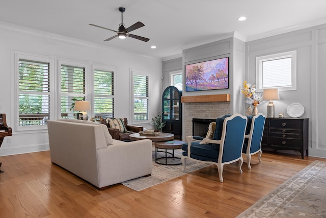 living room with ornamental molding, light hardwood / wood-style floors, ceiling fan, and a fireplace