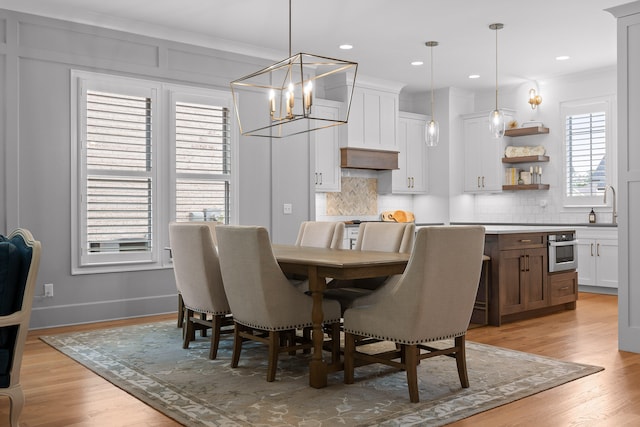 dining space featuring a notable chandelier, light wood-type flooring, and ornamental molding