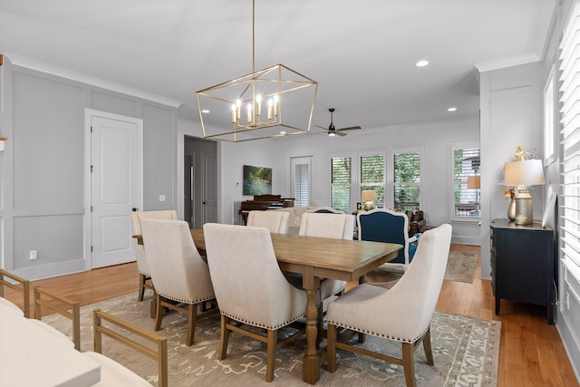 dining area featuring light wood-type flooring, ceiling fan with notable chandelier, and crown molding