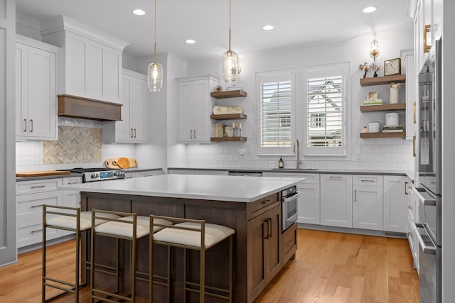 kitchen featuring white cabinetry, a breakfast bar, a kitchen island, decorative light fixtures, and sink