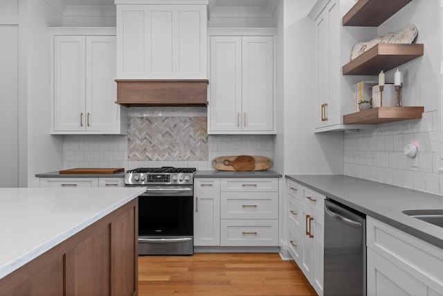 kitchen featuring appliances with stainless steel finishes, backsplash, light hardwood / wood-style floors, and white cabinets