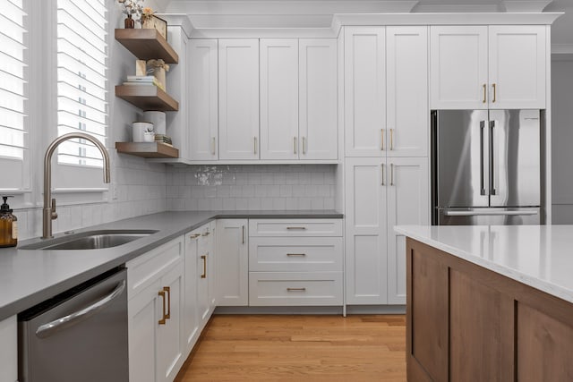 kitchen with light hardwood / wood-style floors, stainless steel appliances, sink, and white cabinetry