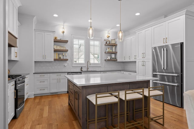 kitchen featuring white cabinets, sink, a kitchen island, stainless steel appliances, and a kitchen bar