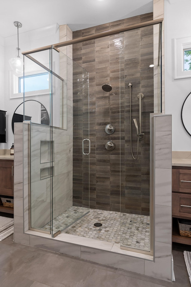 bathroom featuring plenty of natural light, vanity, tile patterned flooring, and a shower with shower door