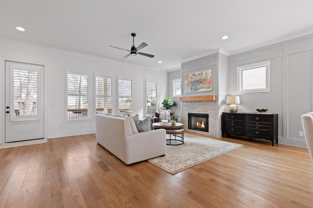 living room with ornamental molding, ceiling fan, and light hardwood / wood-style floors