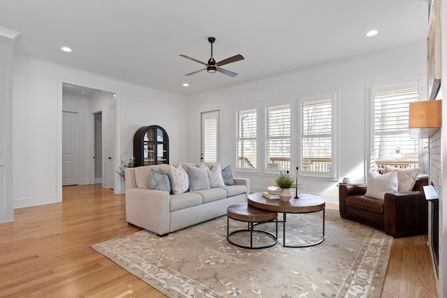 living room with ornamental molding, ceiling fan, and light wood-type flooring