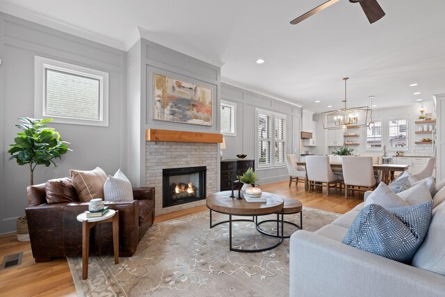 living room featuring plenty of natural light, light hardwood / wood-style floors, and a brick fireplace