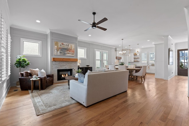 living room with crown molding, ceiling fan with notable chandelier, and light hardwood / wood-style floors