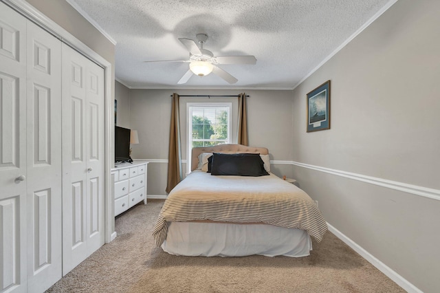 carpeted bedroom featuring a textured ceiling, ornamental molding, ceiling fan, and a closet