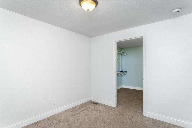 carpeted spare room with a textured ceiling