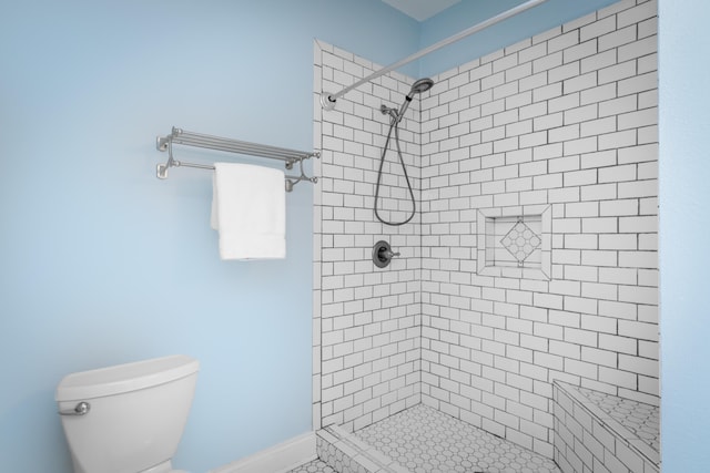 bathroom with a tile shower and toilet