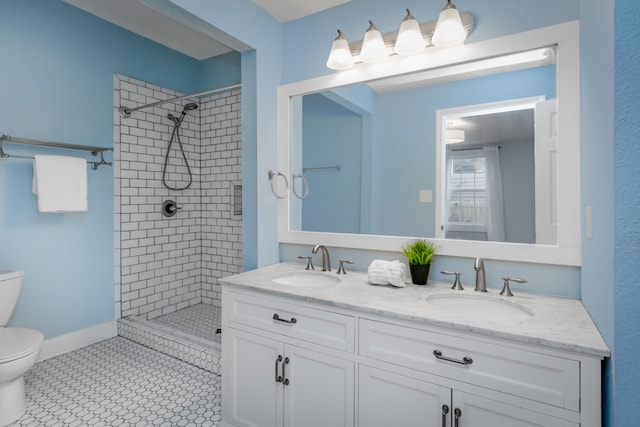 bathroom with a tile shower, tile patterned floors, vanity, and toilet