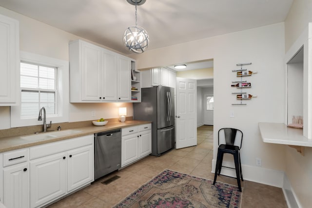 kitchen with stainless steel appliances, white cabinetry, hanging light fixtures, and sink