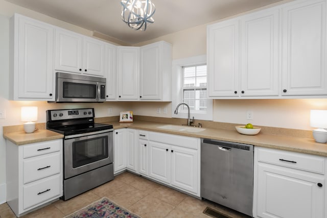 kitchen featuring a notable chandelier, white cabinets, appliances with stainless steel finishes, and sink