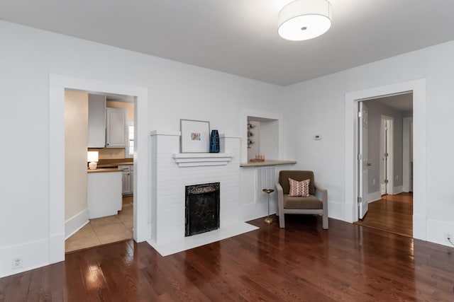 unfurnished room featuring a brick fireplace and dark hardwood / wood-style flooring