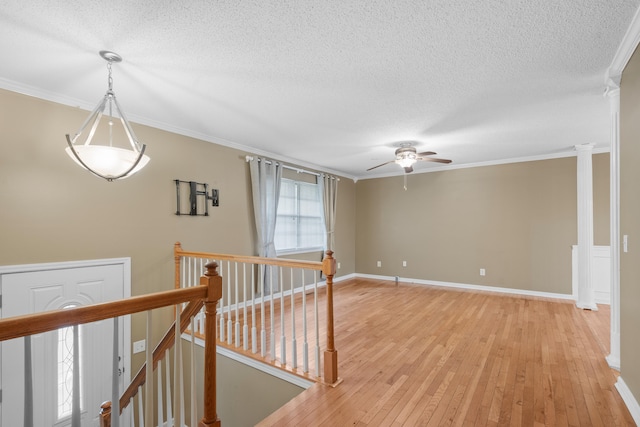 hallway featuring a textured ceiling, crown molding, and light hardwood / wood-style flooring