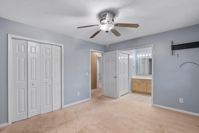 unfurnished bedroom with light carpet, a closet, connected bathroom, and ceiling fan