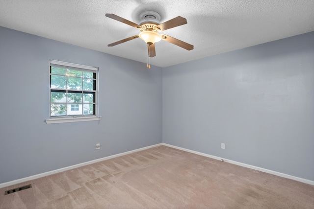 empty room with light carpet, ceiling fan, and a textured ceiling