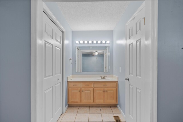 bathroom with ceiling fan, vanity, tile patterned flooring, and a textured ceiling