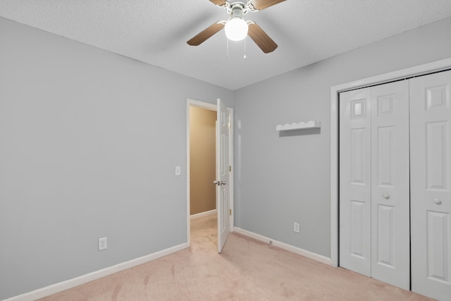 unfurnished bedroom with ceiling fan, light colored carpet, a textured ceiling, and a closet