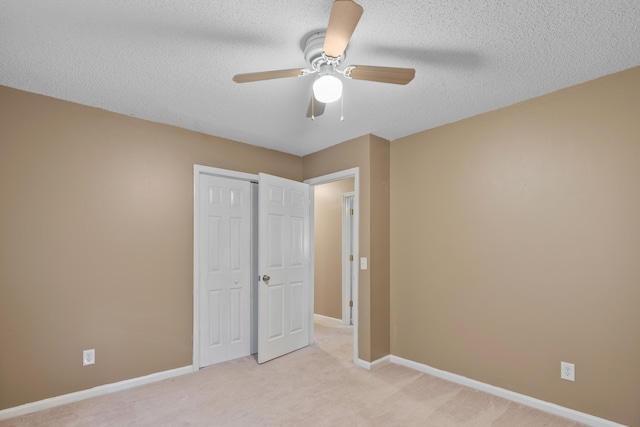 unfurnished bedroom featuring a textured ceiling, ceiling fan, light colored carpet, and a closet