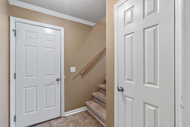 staircase with a textured ceiling, crown molding, and tile patterned floors