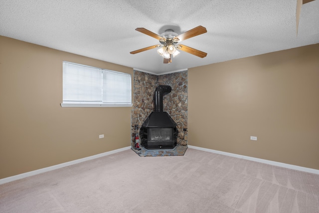 interior space featuring ceiling fan, carpet floors, a textured ceiling, and a wood stove