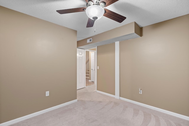 carpeted spare room featuring ceiling fan and a textured ceiling