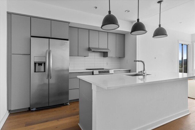 kitchen with dark hardwood / wood-style floors, stainless steel refrigerator with ice dispenser, a center island with sink, and sink