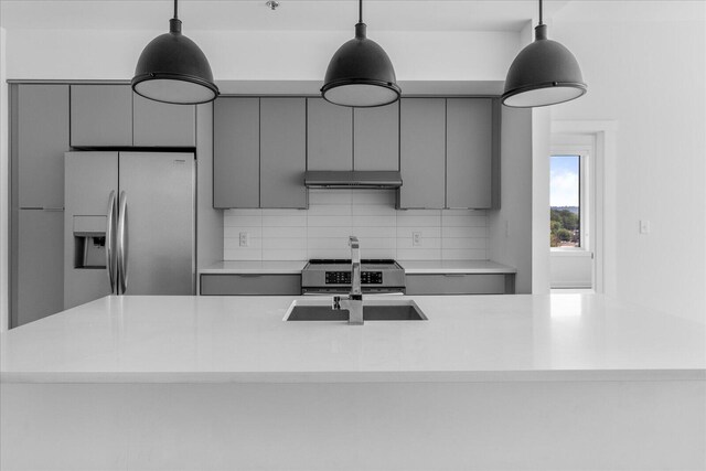 kitchen with pendant lighting, sink, gray cabinets, appliances with stainless steel finishes, and decorative backsplash