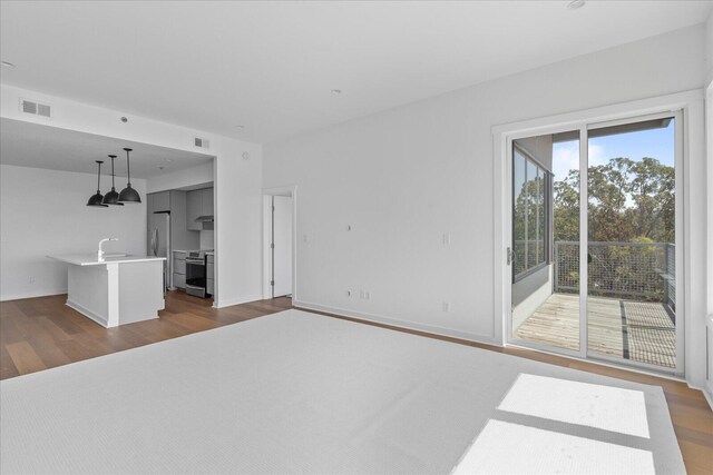 unfurnished living room featuring wood-type flooring and sink