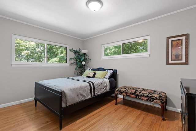 bedroom with light wood-type flooring, crown molding, and multiple windows