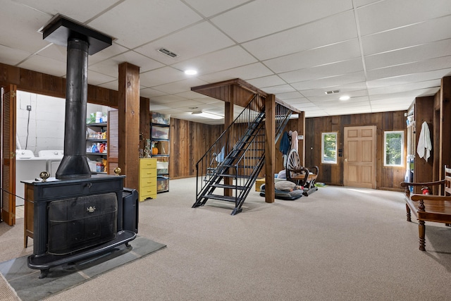 exercise area featuring carpet flooring, wooden walls, washer and dryer, and a paneled ceiling