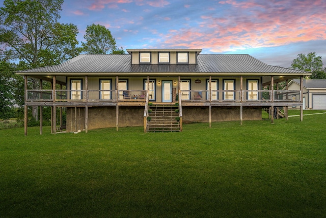 back house at dusk featuring a lawn and a garage