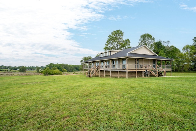 back of house featuring a rural view, a deck, and a lawn