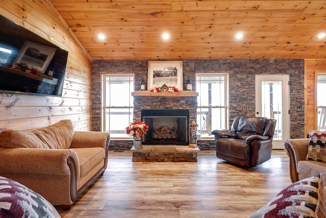 living room featuring a stone fireplace, lofted ceiling, wood ceiling, and a healthy amount of sunlight