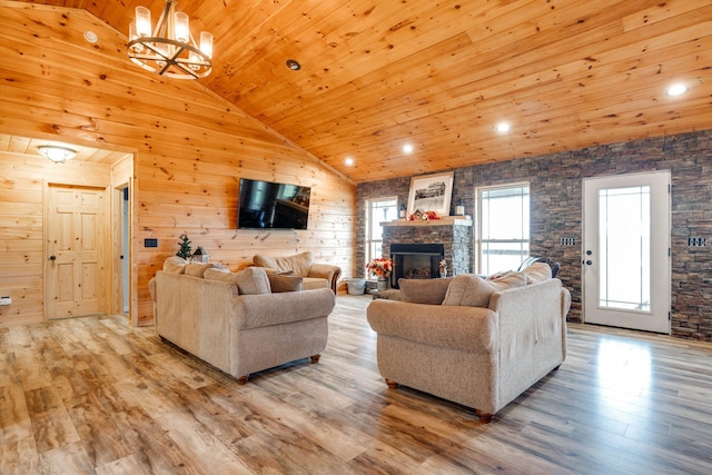 living room with wood ceiling, high vaulted ceiling, a stone fireplace, wood walls, and light hardwood / wood-style flooring